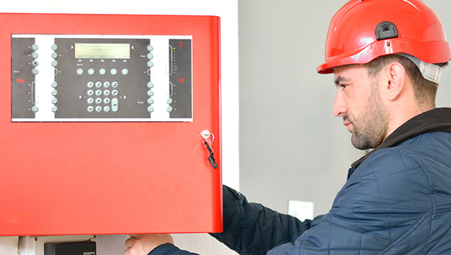 Man with a hardhat working on a red access panel - Pavion Fire Safety, Integration, and Security